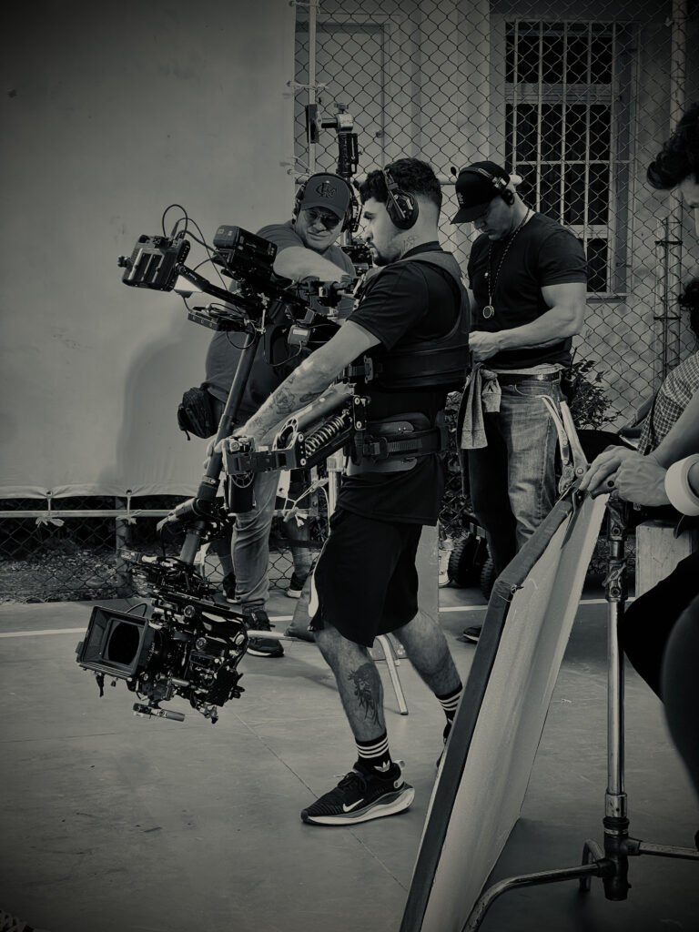 Registro do operador de Steadicam Leandro Brígido ajustando o equipamento durante gravações externas. Imagem reflete a dedicação à captura fluida em produções cinematográficas.